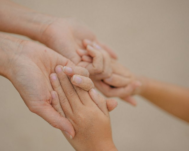 Eine große Hand hält eine kleine Kinderhand