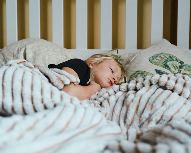 Schlafendes Kind unter einer gestreiften Decke