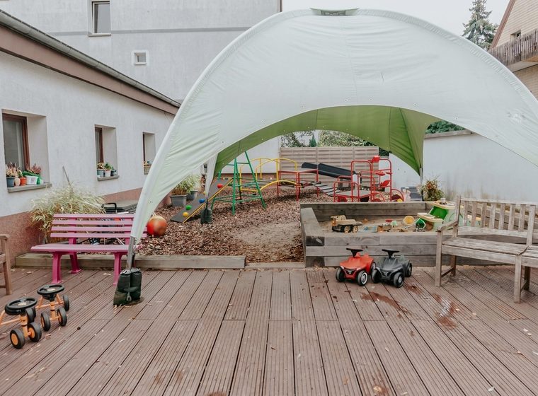 Außengelände mit Sonnensegel, Sandkasten, Terrasse und Kinderfahrzeugen